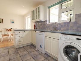 A kitchen with a sink, dishwasher, and washing machine at Cloudbreak in Wadebridge