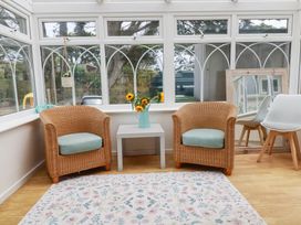 A conservatory with two armchairs and a coffee table at Cloudbreak in Wadebridge