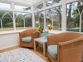 A conservatory with two rattan chairs and a table at Cloudbreak in Wadebridge