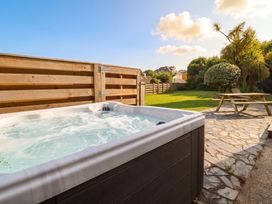 A hot tub and picnic table in an outdoor area at Cloudbreak in Wadebridge