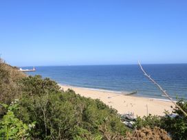 A beach view with people and a pier at The Pines Bournemouth