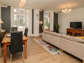 A living room with a sofa, dining table, and television at The Pines in Bournemouth