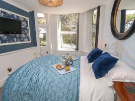A bedroom with a bed, a television, and a tray with food and drinks at The Pines in Bournemouth