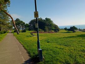 A park with a pathway, trees, and ocean view at The Pines in Bournemouth