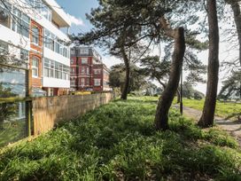 A garden with trees and grass alongside buildings at The Pines in Bournemouth