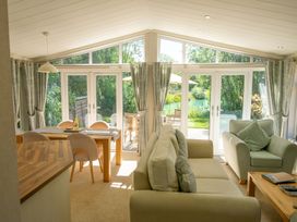 A living room with a sofa and dining table at Ash Lodge in Stowmarket