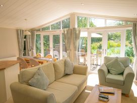A living room with a sofa and dining area at Ash Lodge in Stowmarket