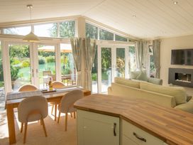 A living room with a dining table and sliding doors at Ash Lodge in Stowmarket