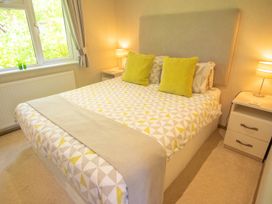 A bedroom with a bed and bedside table at Ash Lodge in Stowmarket
