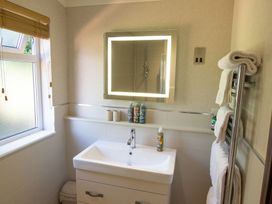 A bathroom with a sink, mirror, and towels at Ash Lodge in Stowmarket
