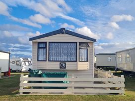 A caravan with a front window and fence at Stoup Cross Caravan Park in Whitby