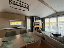 A living room with a dining table and kitchen area at Haggerston Castle - Lakeside Retreat in Berwick-upon-Tweed