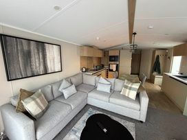 A living room with a sofa and kitchen area at Haggerston Castle - Lakeside Retreat Berwick-upon-Tweed