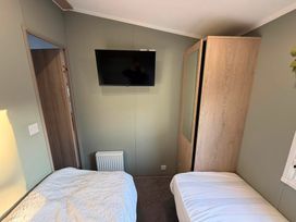 A bedroom with twin beds and a television on the wall at Haggerston Castle - Lakeside Retreat, Berwick-upon-Tweed