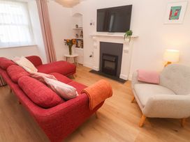 A living room with a sofa, armchair, television, and fireplace at Top Deck in St. Ives