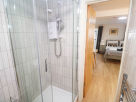 A bathroom with a shower and doorway leading to a bedroom at The Cabin St Ives
