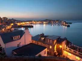 A view of a harbor with boats and lights in the evening at The Cabin in St Ives