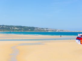 A beach with kites flying over the water at The Cabin in St Ives