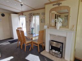 A dining room with a table, chairs, and a fireplace at Beachcomber Cabin Dog Friendly Anderby Creek in Lincolnshire
