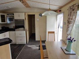 A kitchen with cabinets and a dining table at Beachcomber Cabin Dog Friendly Anderby Creek Lincolnshire