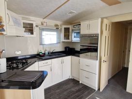 A kitchen with cabinets, sink, and stove at Beachcomber Cabin Dog Friendly Anderby Creek Lincolnshire