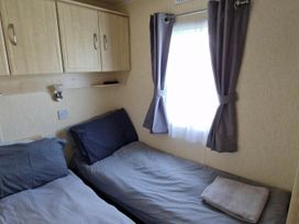 A bedroom with two beds and a window at Beachcomber Cabin Dog Friendly Anderby Creek Lincolnshire