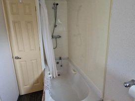 A bathroom with a shower over a bathtub and a door at Beachcomber Cabin Dog Friendly Anderby Creek Lincolnshire