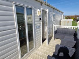 An outdoor area with a sliding glass door and seating at Beachcomber Cabin Dog Friendly Anderby Creek Lincolnshire