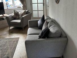 A living room with a sofa, armchair, and television and door at the property