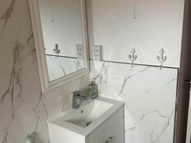 A sink with a mirror and wall hooks at a property