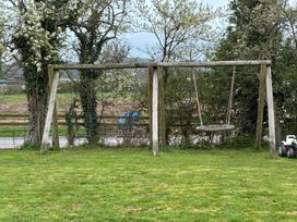 A swing set in a yard with grass and trees at the property