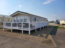A mobile home with wooden decking and gravel outside at a holiday park