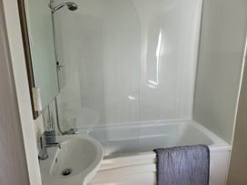 A bathroom with a shower over a bathtub and a sink at the property