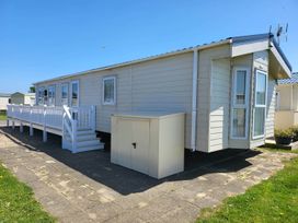 A mobile home with a deck and storage shed in a park setting