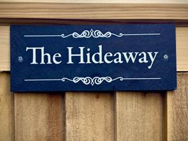A sign that reads The Hideaway mounted on a wooden fence