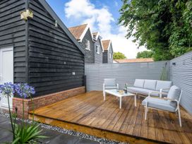 A wooden decking area with seating and a table at Detached House in Quiet Village Pets Allowed Ashbocking near Otley, Suffolk