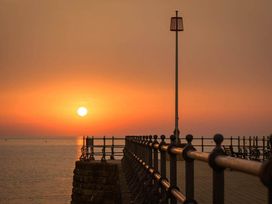 A pier with a railing at sunset at 4 Bed Sleeps 8 Pool Table Sea View Parking, Swanage