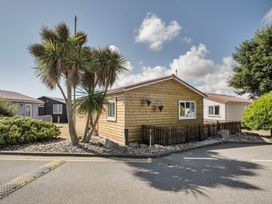 A wooden cabin with palm trees and a gravel area at Seaside Chalet Retreat in Bridlington