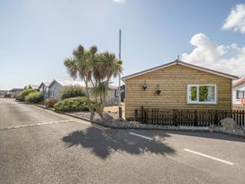 A wooden cabin with palm trees and a road at Seaside Chalet Retreat in Bridlington
