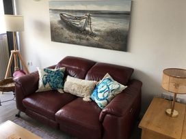 A living room with a red sofa and a lamp at Torpoint Apartment Sleeps4 Seaside Parking in Downderry