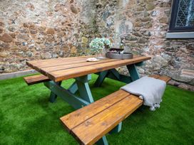 A picnic table with flowers and a wine bottle in an outdoor seating area at Stunning 3 Bed Converted Village Hall Near Kelso Nenthorn near Kelso