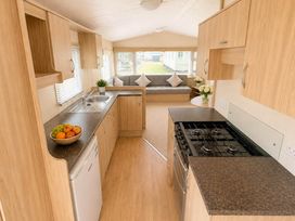 A kitchen with a sink, gas stove, and sofa at Billing Aquadrome Holiday Park 2bed Caravan Northampton