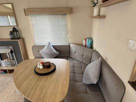 A dining room with a round table and sofa seating at Billing Aquadrome Holiday Park 2bed Caravan Northampton