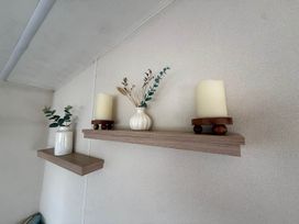 A shelf with candles and a vase at Billing Aquadrome Holiday Park 2bed Caravan Northampton