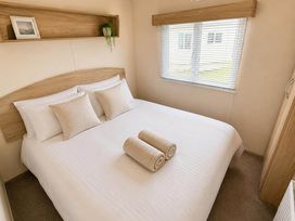 A bedroom with a double bed and towels at Billing Aquadrome Holiday Park 2bed Caravan Northampton