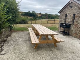 An outdoor seating area with a table and benches near a stone building at a property