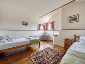 A bedroom with two beds, a chair, and a rug at 16th Century Devon Farmhouse Stunning Views in Winkleigh