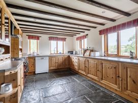 A kitchen with wooden cabinets and appliances at 16th Century Devon Farmhouse Stunning Views in Winkleigh