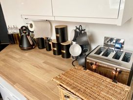 A kitchen counter with kettle, toaster, cups and a basket at Central Tenby 3 Bed Apt Sleeps 6 to 8 Dog Friendly in Tenby