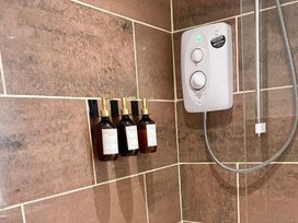A shower with shampoo bottles and a shower unit at Central Tenby 3 Bed Apt Sleeps 6 to 8 Dog Friendly in Tenby